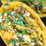 two yellow squash boats filled with food and topped with green onions, pine nuts and cilantro