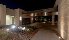 a modern house with lights on the front door and side entrance at night, lit up by outdoor lighting