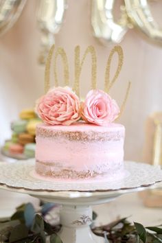 a cake with pink frosting and two flowers on top is sitting on a table