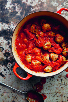 a red pot filled with meatballs and sauce