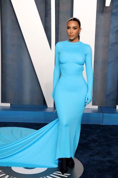 a woman in a blue dress standing on a blue carpet with her long flowing hair