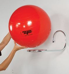 a woman is holding an exercise ball in front of her head and the wall behind her