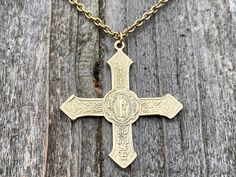 This is an antique replica of a gorgeous and very rare French Saint Benedict Cross Medal from the end of the 19th Century. The oxidized (antiqued) solid gold bronze allows the beautiful details to radiate making it more beautiful than my original from France. This cross is a bit more on the feminine side since it is lightweight and adorned with flowers and foliage. The cross measures 1.3 inches. An antique gold 2x3mm cable chain complements the cross beautifully! This necklace is 20 inches long. Antique Miraculous Medal Necklace As Gift, Collectible Historical Jewelry With Antique Finish, Historical Engraved Jewelry Gift, Antique Pendant Necklace For Commemoration, Collectible Antique Finish Historical Jewelry, Historical Medallion Jewelry For Gift, Antique Bronze Jewelry For Commemoration, Vintage Yellow Gold Cross Pendant Necklace, Victorian Antique Gold Necklace For Memorial