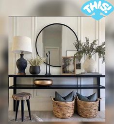 a black console table with two baskets on it and a round mirror over the top