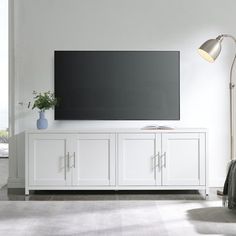 a large flat screen tv mounted to the side of a white cabinet in a living room