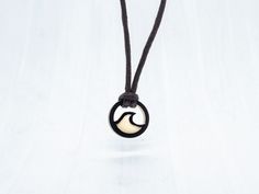 "Still the original and best! This Life Less Ordinary™ wave necklace is the perfect gift for those that want to keep the waves in sight wherever they are. Waterproof and fade resistant, our vegan ivory plaque is as tough as you are. The only other material we use is cotton cord and what we have created is a beach necklace that can join you on all your adventures, from scuba diving to skydiving. DESCRIPTION - Wave Necklace plaque ethically crafted from tagua nut - Cord made from comfortable and durable waxed cotton - 18\" long but can be made longer or shorter to order - Plaque measures 2cm  - Handmade in Brighton, UK A PERFECT LETTERBOX GIFT Not going to see them in time? Live 1000 miles away? No problem! Our wanderlust wave necklace fits right through the letterbox for the perfect vegan g Minimalist Waxed Cord Jewelry For Beach, Black Pendant Jewelry With Waxed Cord, Black Waxed Cord Pendant Jewelry, Black Beach Jewelry With Adjustable Cord, Black Pendant Necklace On Waxed Cord, Black Pendant Necklace With Waxed Cord, Minimalist Black Jewelry For The Beach, Minimalist Black Jewelry For Beach, Black Waxed Cord Necklace For Gift