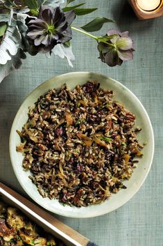 a bowl filled with wild rice next to some flowers