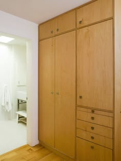 an empty room with wooden cabinets and white towels hanging on the wall behind it,