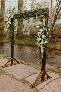 a wooden arch with white flowers and greenery on the top is set up for an outdoor ceremony