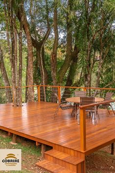 a wooden deck with chairs and table next to trees