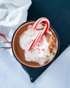 a hot chocolate drink topped with whipped cream and candy canes on top of a table