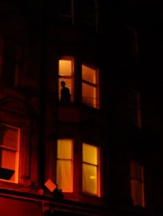 a man standing in the window of a building at night