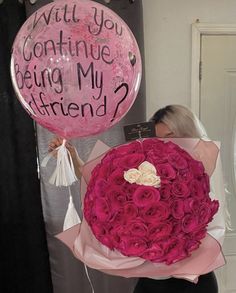 a woman holding a bouquet of pink roses and a balloon that says i will you continue being my friend?