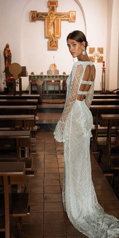 a woman in a white dress is standing in front of pews at a church