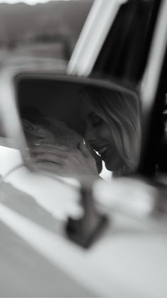 a woman is taking a selfie in the side mirror of a car while holding her phone to her ear