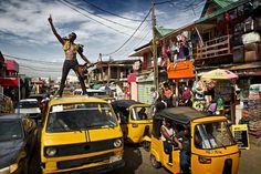 a man standing on top of a yellow car in the middle of a crowded street