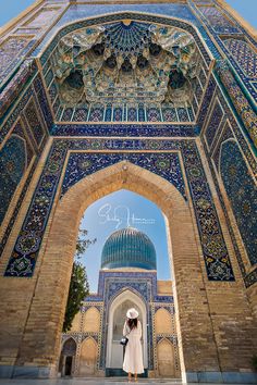 a woman standing in front of an ornate archway