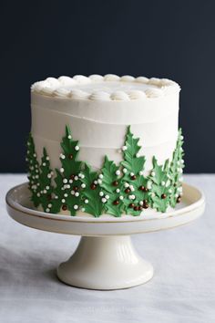 a white frosted cake decorated with holly and berries