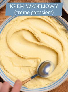 a bowl filled with yellow batter and a spoon in the center, on top of a wooden table