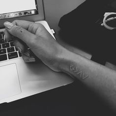 a person with a small tattoo on their left wrist using a laptop and holding onto the keyboard