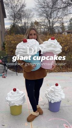 a woman holding giant cupcakes on top of each other