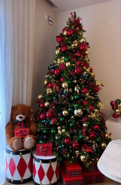 a christmas tree is decorated with red, green and gold ornaments in tin canisters