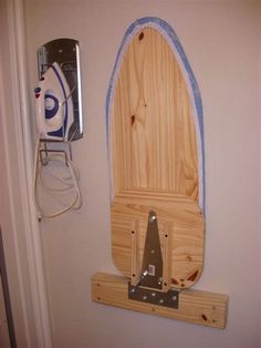 a wooden surfboard mounted to the side of a wall with an ironing board on it