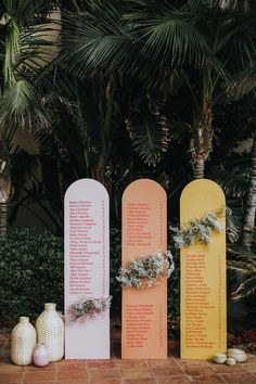 three vases sitting next to each other on top of a brick floor in front of palm trees