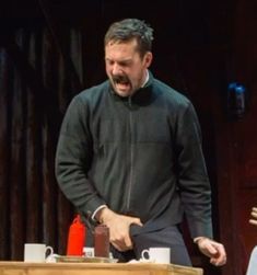 two men standing next to each other in front of a table with cups on it