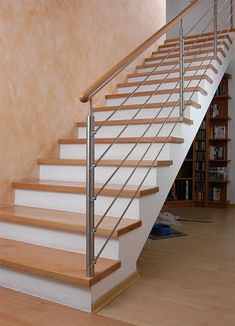 there is a white stair case next to the bookshelf