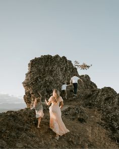 three people walking up a hill with one woman in a white dress and the other man in a black shirt