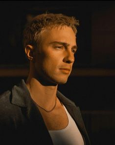 a man in a white shirt and black jacket looking off into the distance with his eyes closed