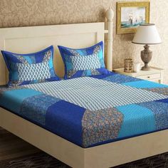 a bed with blue and white bedspread in a bedroom next to a lamp