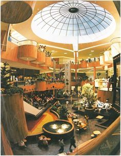 an overhead view of a mall with people sitting and standing in the lobby, looking up at the ceiling