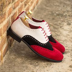 a pair of red and white shoes leaning against a brick wall