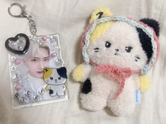 a keychain with an image of a cat on it next to a small stuffed animal