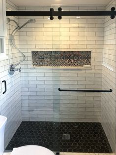 a white toilet sitting next to a shower in a bathroom with black and white tile