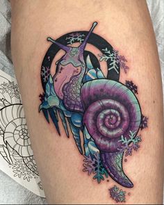 a woman's thigh with an artistic tattoo design on her leg and the image of a snail