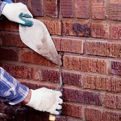 a brick wall being painted by a person with gloves on and one hand holding a paint roller