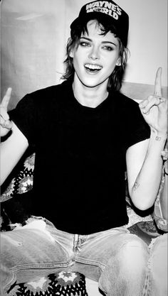 a black and white photo of a woman sitting on the floor with her fingers up