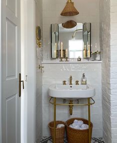 a white sink sitting under a bathroom mirror next to a basket filled with toilet paper