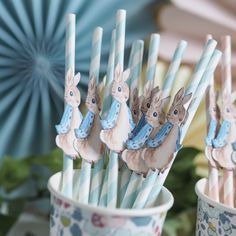 there are many toothbrushes in the cups with rabbits on them and blue paper umbrellas behind them