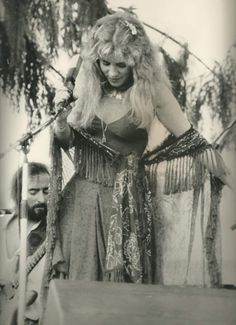 an old photo of a woman with long hair and fringes on her head standing next to a man