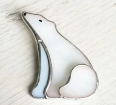 a white polar bear pin sitting on top of a wooden table next to a piece of paper