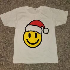 Brand New Never Worn With Tags. Boutique. Smile Emoji Red Santa Hat Christmas Graphic T-Shirt. True To Size. Limited Sizes! Perfect Condition. Smoke Free And Pet Free Home Cute Red T-shirt For Winter, Cute Red Winter T-shirt, Fun White T-shirt For Holiday, Fun White Holiday Tops, Fun White Christmas Tops, Fun Red Top As A Gift, Smile Emoji, Red Santa Hat, Boutique Shirts