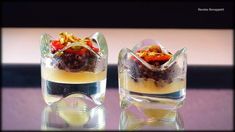 two desserts are sitting on top of each other in small glass dishes with fruit and nuts