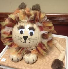 a stuffed animal lion sitting on top of a wooden table next to a cat toy