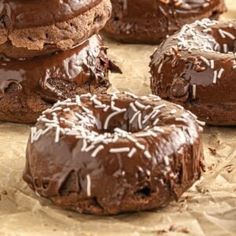 chocolate doughnuts with sprinkles on top of each one sitting on wax paper