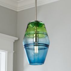 a blue and green glass light fixture hanging from a ceiling in a room with white walls