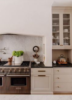 a kitchen with marble counter tops and white cabinets, along with an oven in the center